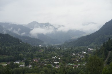 Photo of Picturesque view of houses and forest in mountains under blue sky