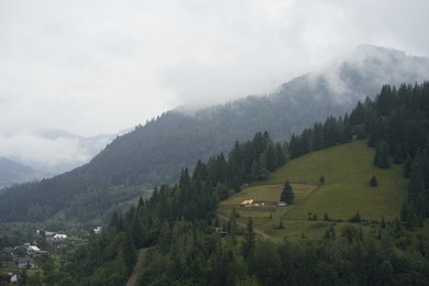 Photo of Picturesque view of houses and forest in mountains under blue sky