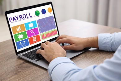 Image of Payroll data. Man working on laptop at table, closeup