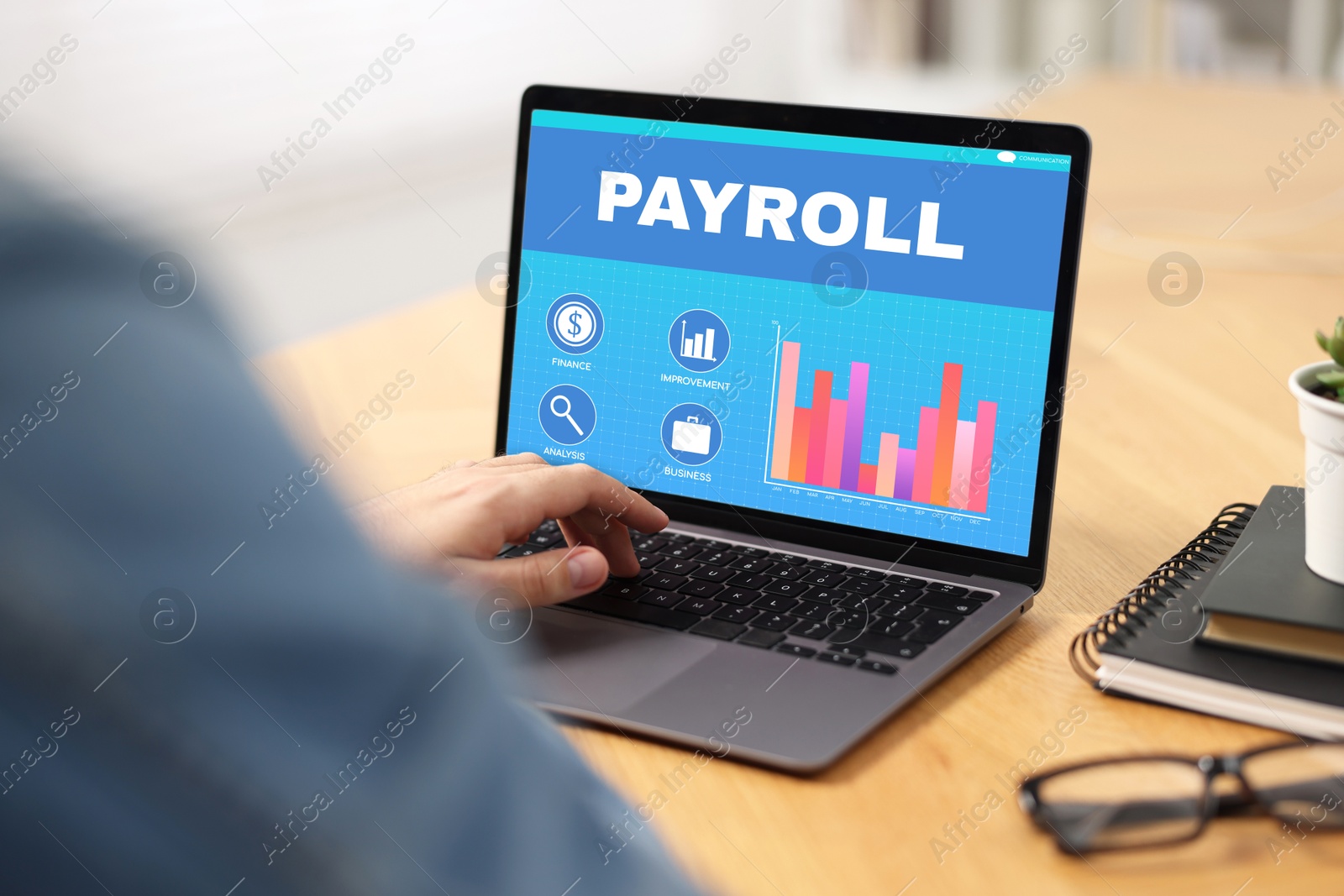 Image of Payroll data. Man working on laptop at table, closeup