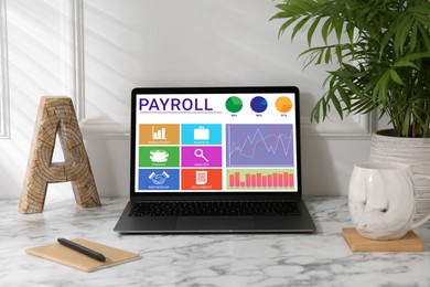 Image of Laptop with payroll data on screen on table