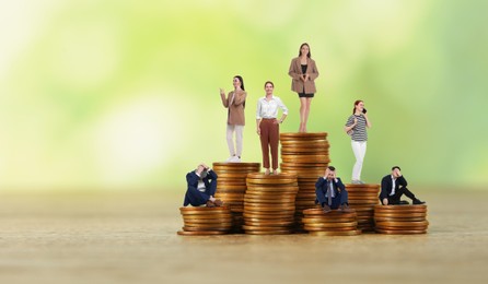 Women standing on higher stacks of coins than men against blurred background, banner design with space for text