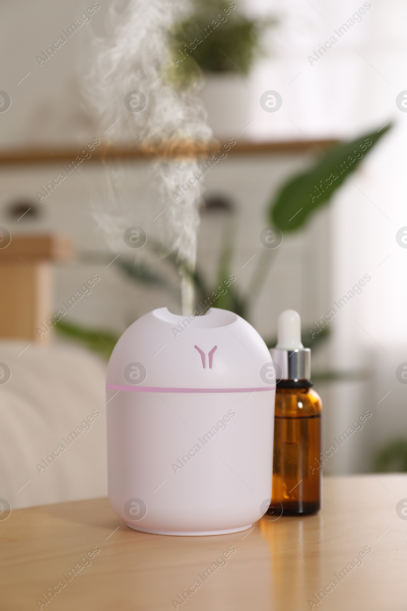 Image of Aroma diffuser and bottle of essential oil on table in room