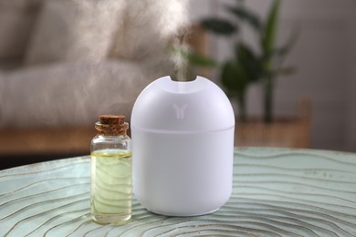 Aroma diffuser and bottle of essential oil on table in room