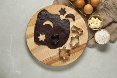 Photo of Raw dough, cookie cutters and ingredients on grey marble table, top view