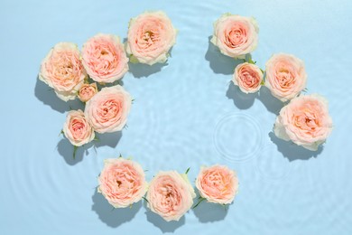 Photo of Beautiful rose flowers in water on light blue background, top view. Space for text