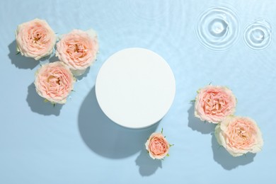 Photo of Beautiful rose flowers and round shaped podium in water on light blue background, flat lay