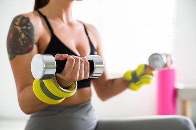 Woman with ankle weights and dumbbells training indoors, closeup