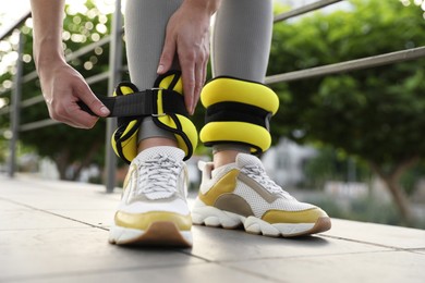 Woman putting on ankle weights outdoors, closeup