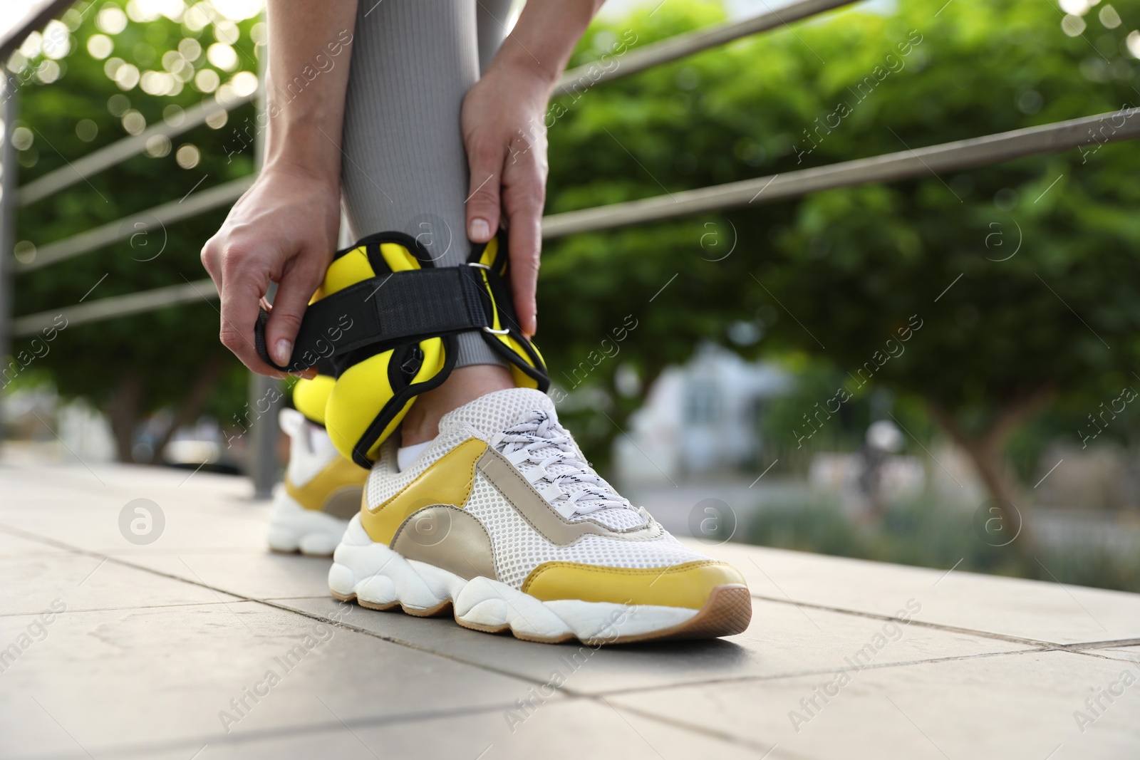 Photo of Woman putting on ankle weights outdoors, closeup