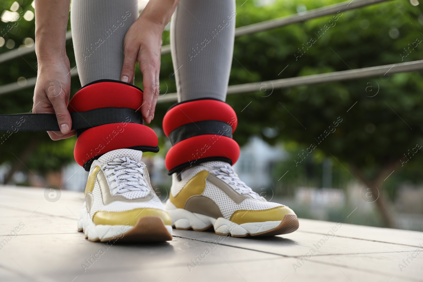 Photo of Woman putting on ankle weights outdoors, closeup