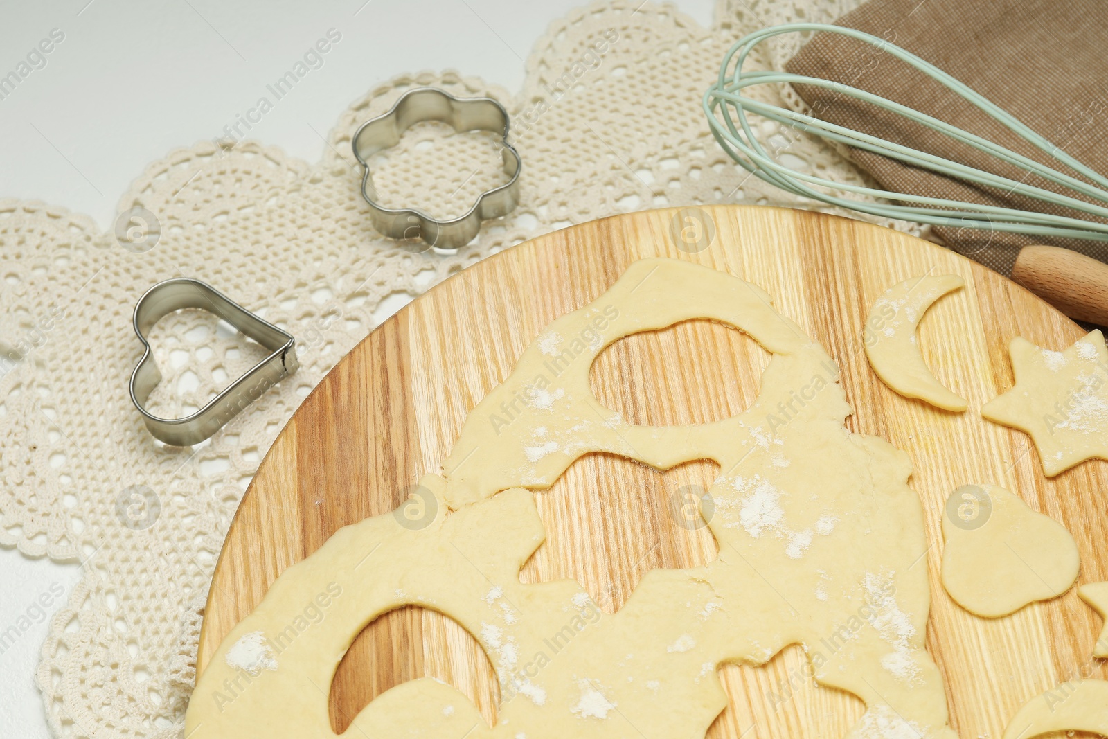 Photo of Raw dough and cookie cutters on white table, above view