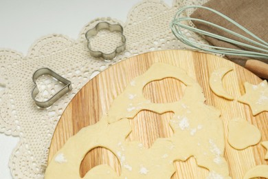 Photo of Raw dough and cookie cutters on white table, above view