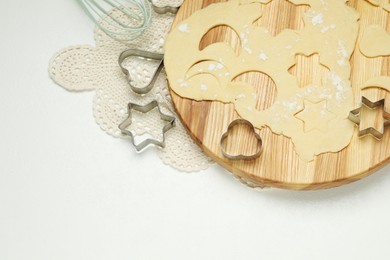 Photo of Raw dough and cookie cutters on white table, above view. Space for text