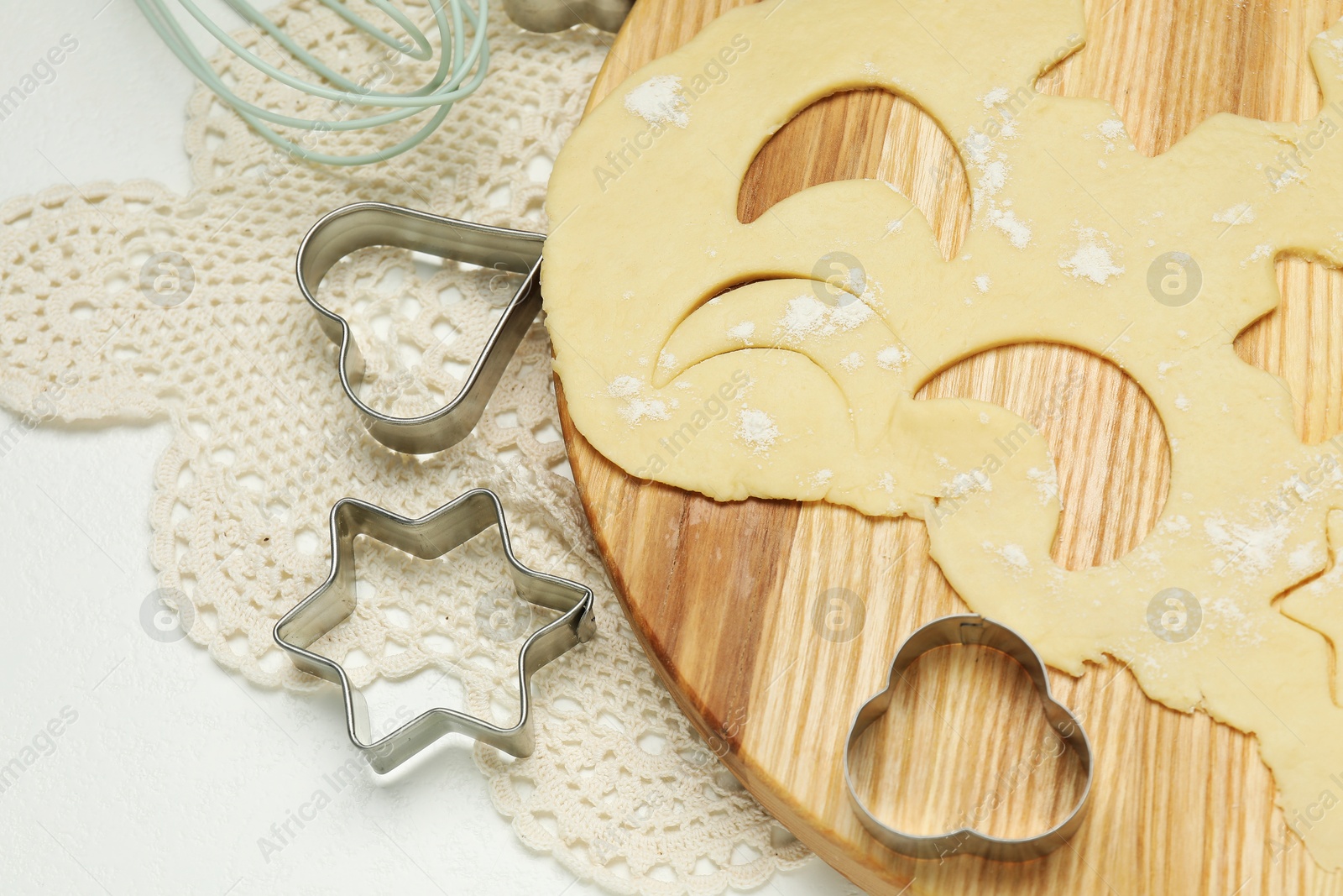 Photo of Raw dough and cookie cutters on white table, above view