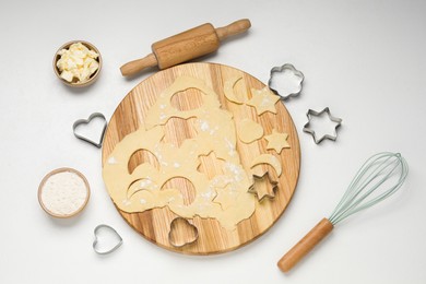 Photo of Raw dough, cookie cutters, rolling pin, butter and flour on white table, flat lay