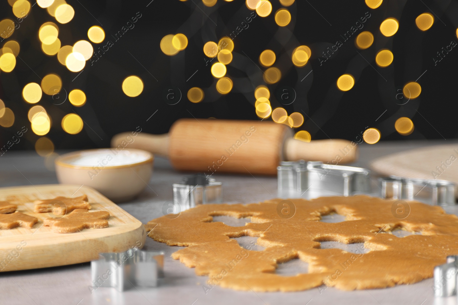 Photo of Raw dough, cookie cutters and rolling pin on grey table, closeup