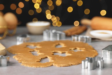 Photo of Raw dough and cookie cutters on grey table, closeup