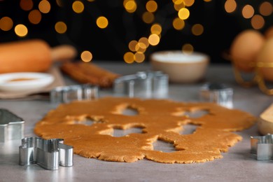 Photo of Raw dough and cookie cutters on grey table, closeup