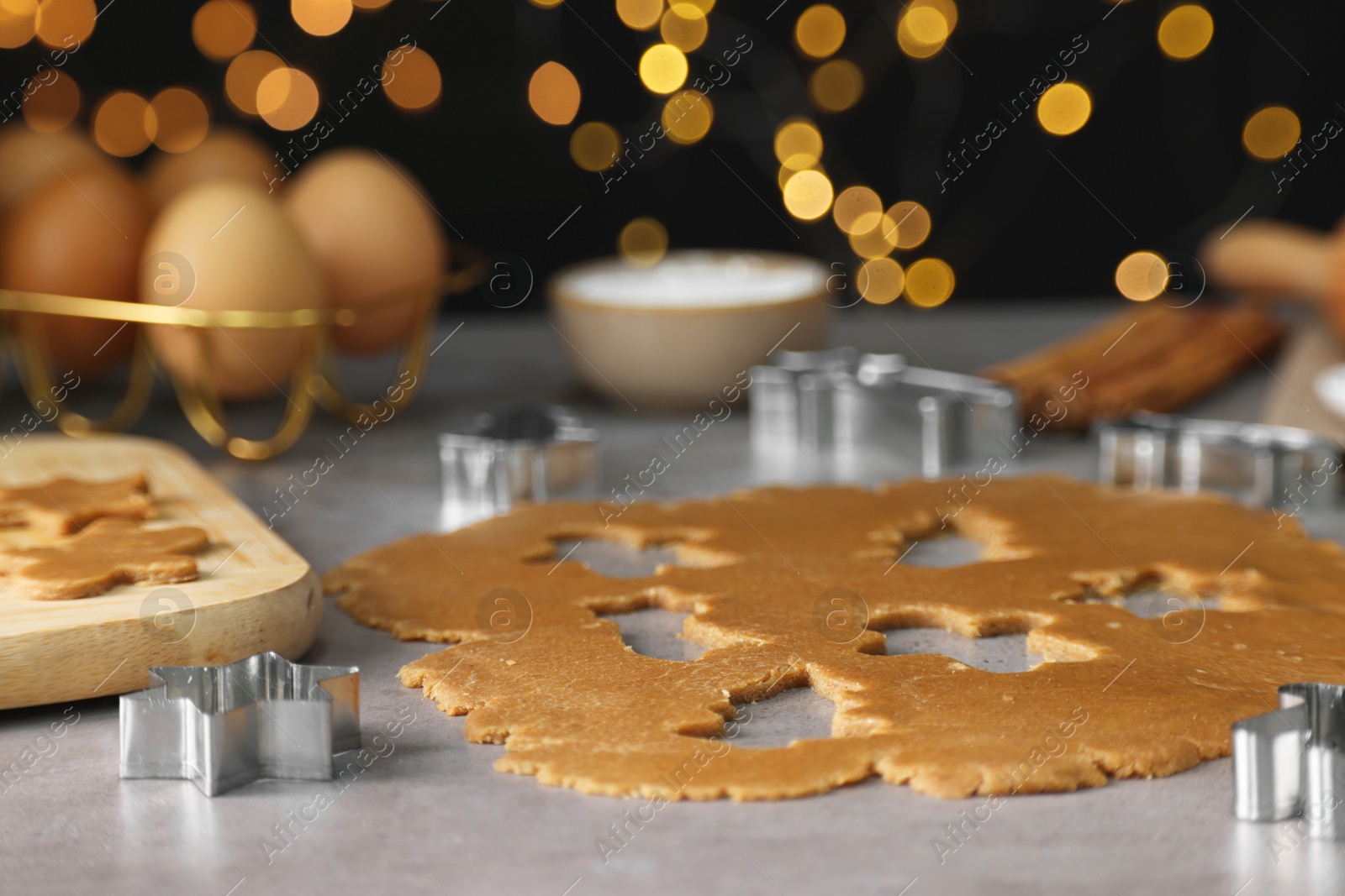 Photo of Raw dough and cookie cutters on grey table, closeup