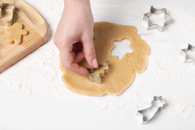 Woman making cookies with cutters at white table, closeup