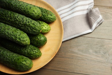 Photo of Fresh green cucumbers on wooden table, space for text