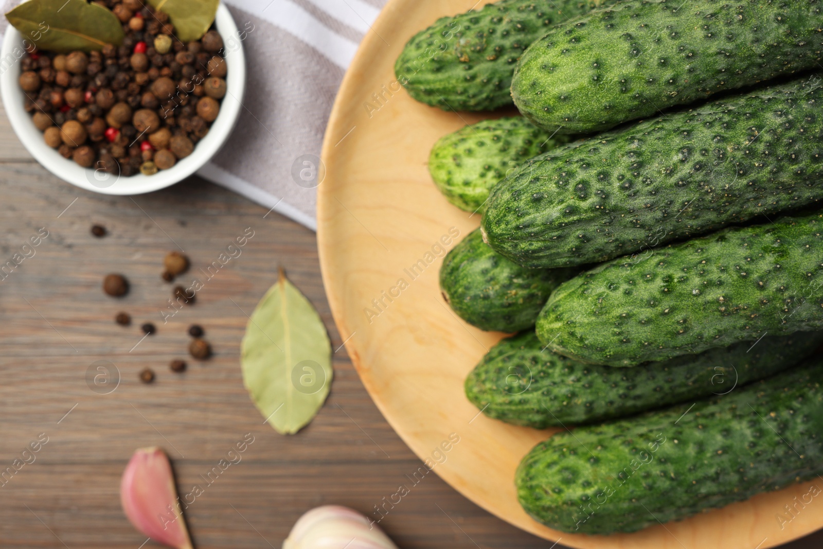 Photo of Fresh green cucumbers and spices on wooden table, above view