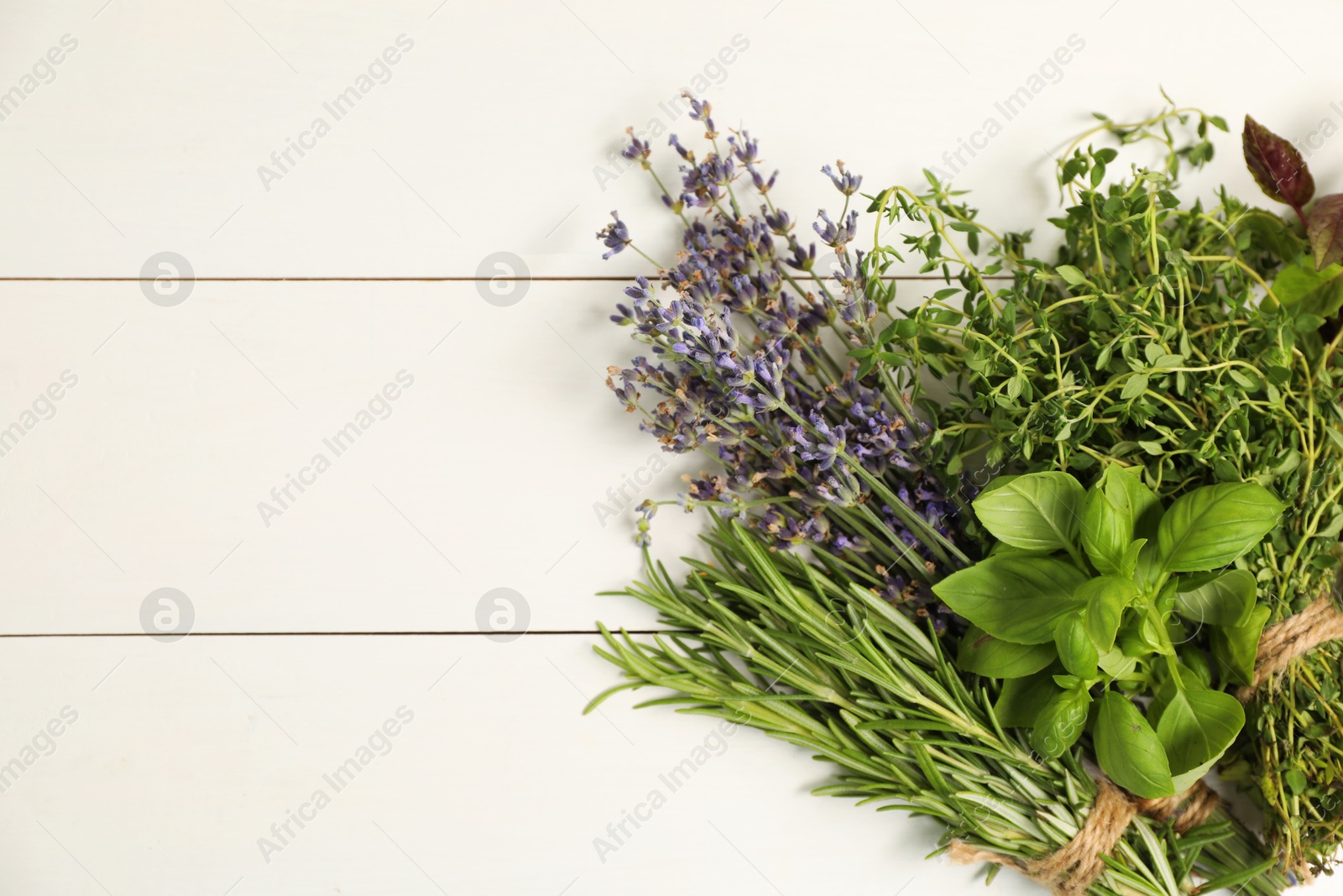 Photo of Different aromatic herbs on white wooden table, top view. Space for text