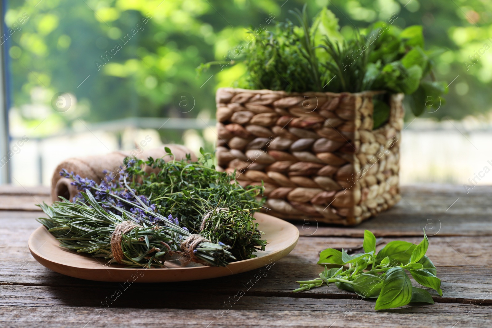 Photo of Different aromatic herbs on wooden table against blurred background