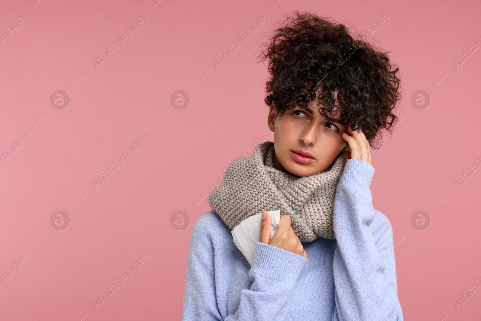 Photo of Cold symptom. Young woman with tissue on pink background