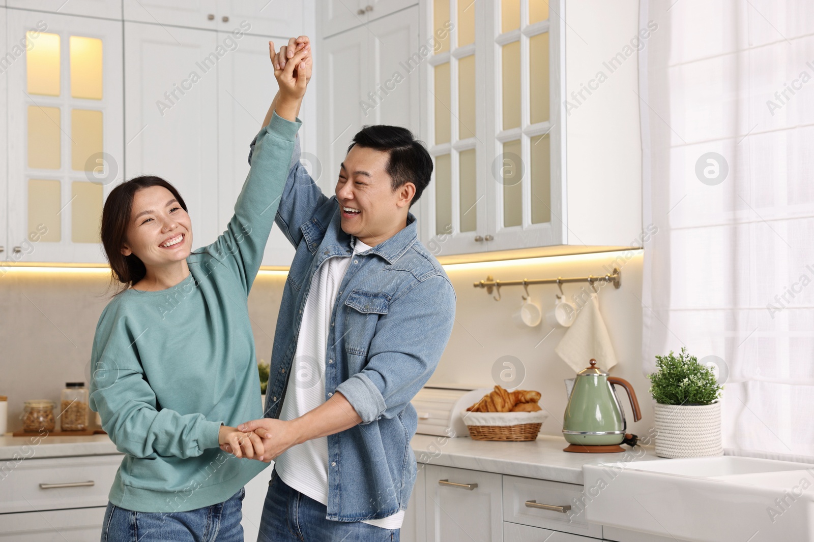 Photo of Happy lovely couple dancing together in kitchen