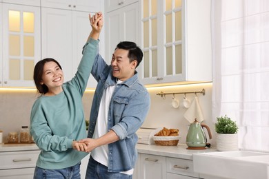 Happy lovely couple dancing together in kitchen