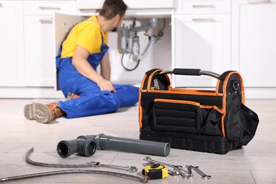 Photo of Professional plumber fixing piping system at home, focus on tools