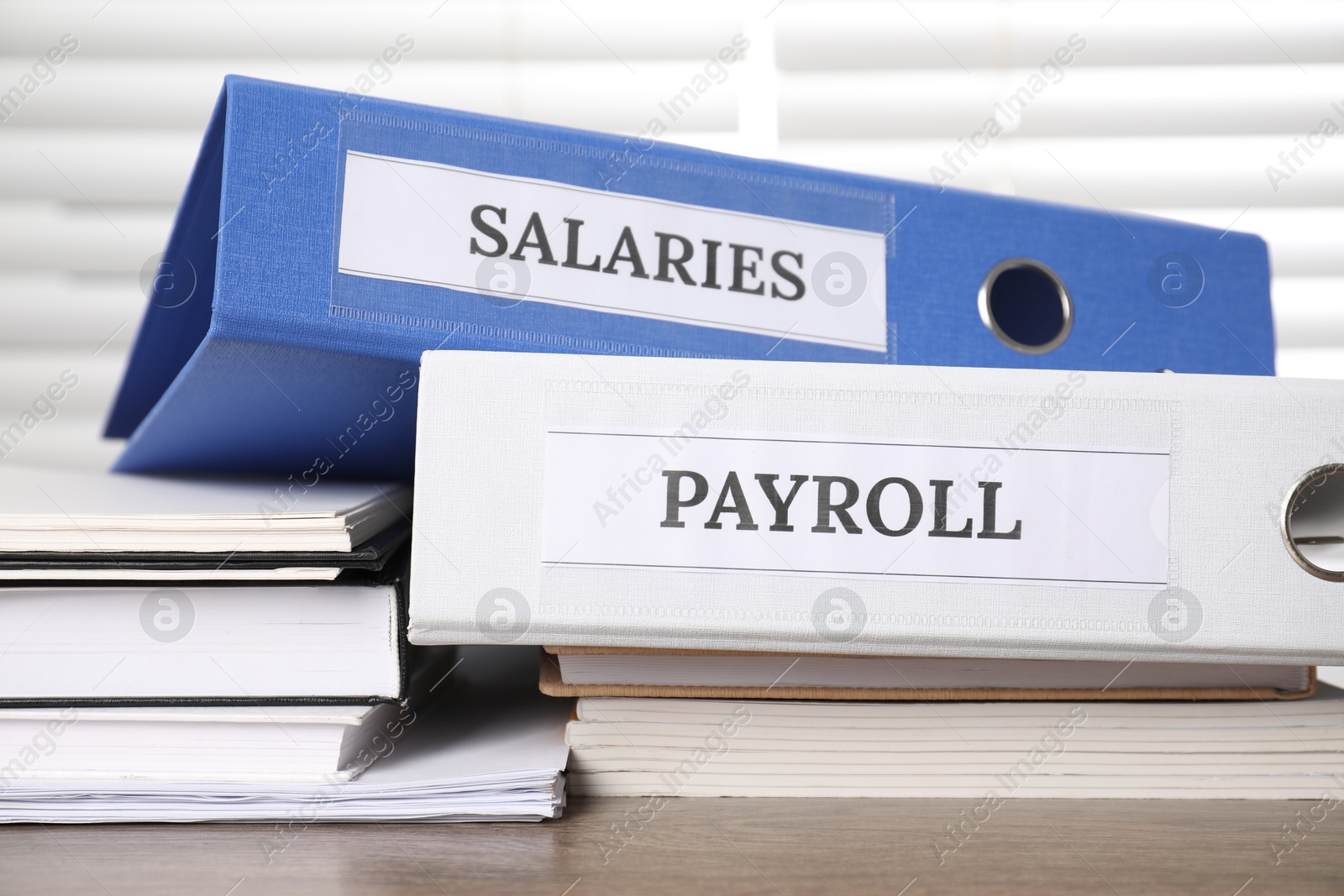 Photo of Office folders with words Payroll and Salaries on wooden table, closeup