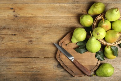 Photo of Fresh green pears, leaves and knife on wooden table, flat lay. Space for text