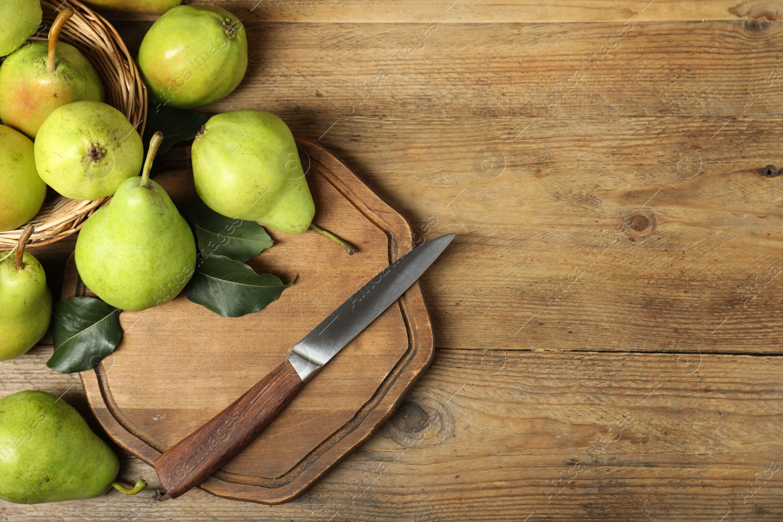 Photo of Fresh green pears, leaves and knife on wooden table, flat lay. Space for text