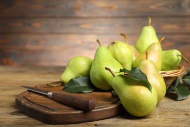 Photo of Fresh green pears, leaves and knife on wooden table, closeup. Space for text