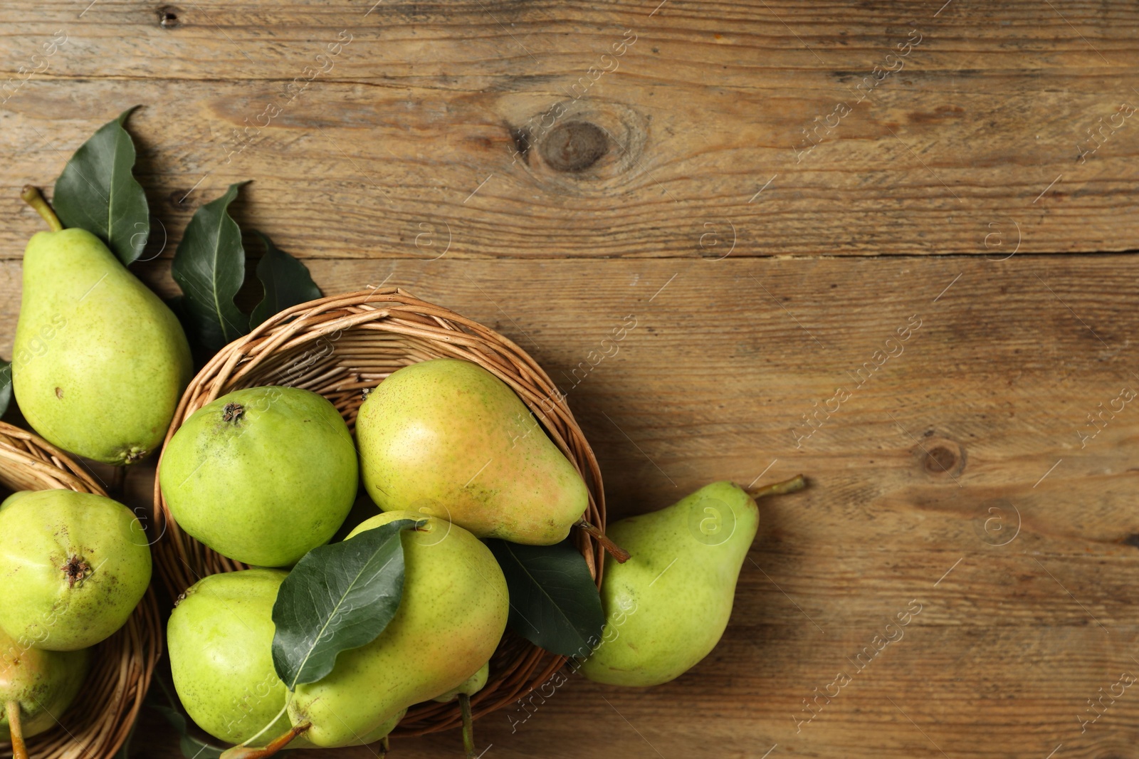 Photo of Fresh green pears and leaves on wooden table, flat lay. Space for text