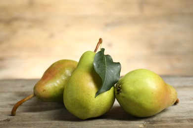 Photo of Fresh green pears and leaf on wooden table, closeup