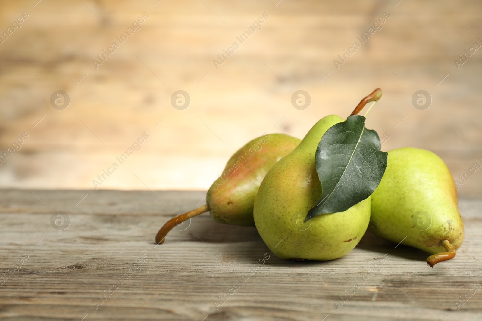 Photo of Fresh green pears and leaf on wooden table. Space for text