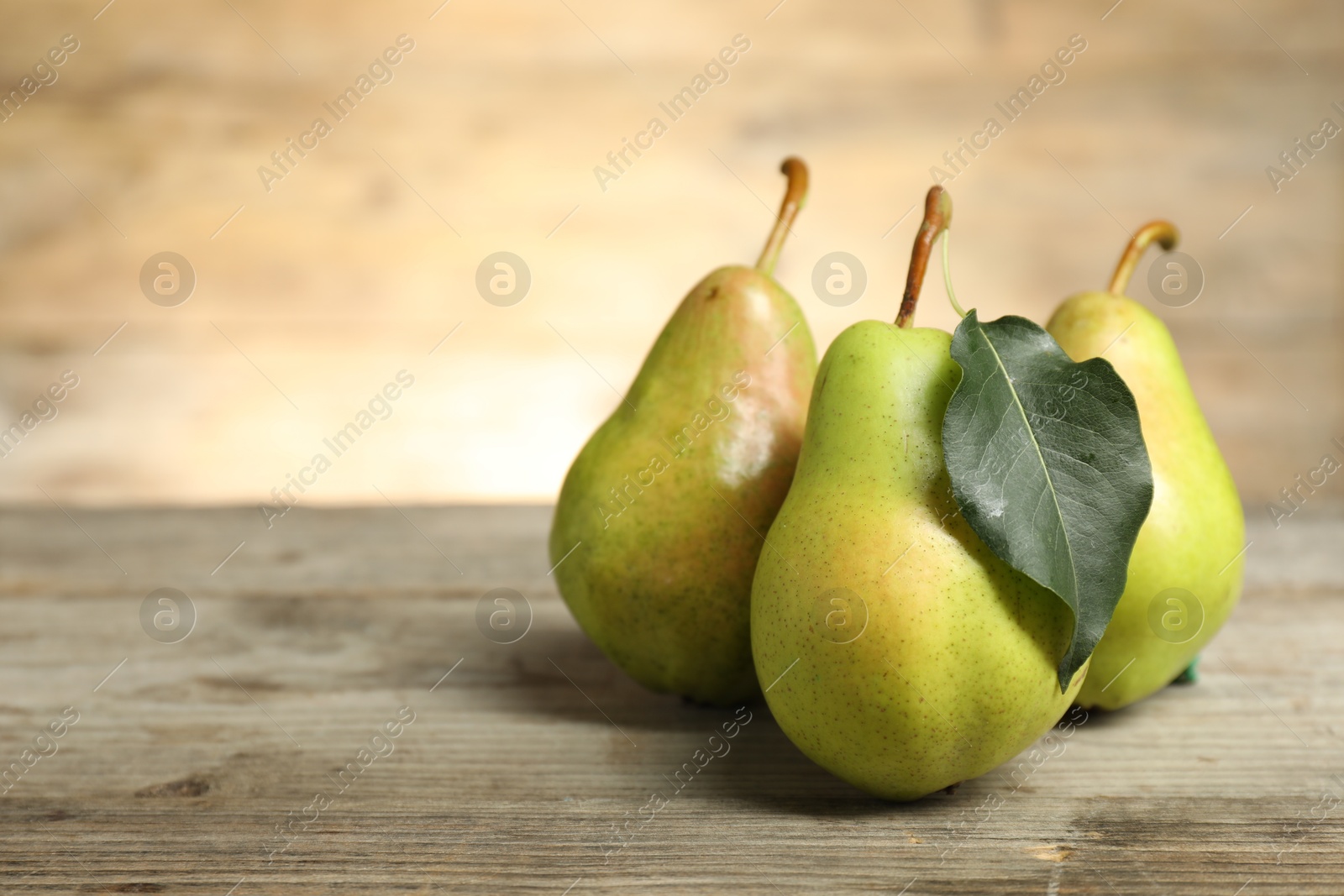 Photo of Fresh green pears and leaf on wooden table. Space for text