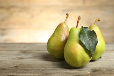 Photo of Fresh green pears and leaf on wooden table. Space for text