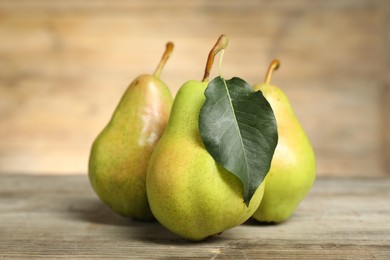 Photo of Fresh green pears and leaf on wooden table, closeup