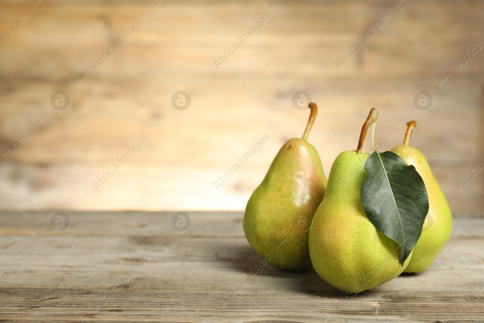 Photo of Fresh green pears and leaf on wooden table. Space for text