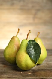 Photo of Fresh green pears and leaf on wooden table, closeup