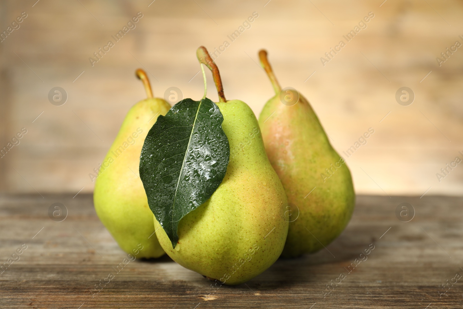 Photo of Fresh green pears and leaf on wooden table, closeup