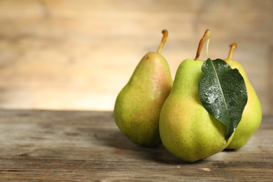 Photo of Fresh green pears and leaf on wooden table, closeup. Space for text