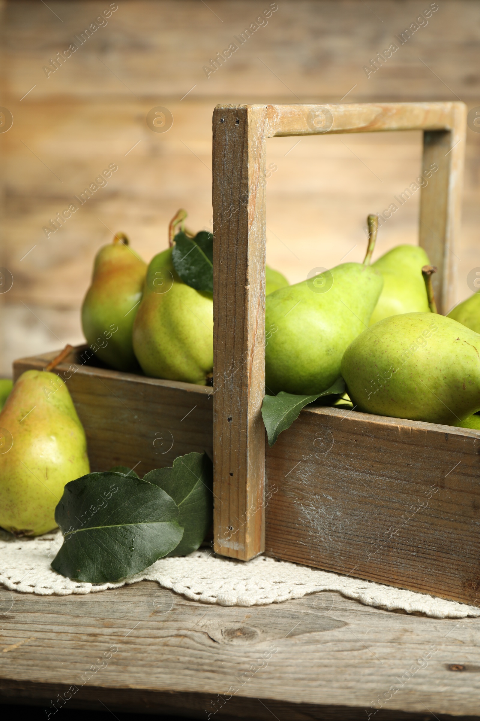 Photo of Crate with fresh green pears and leaves on wooden table