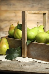 Photo of Crate with fresh green pears and leaves on wooden table