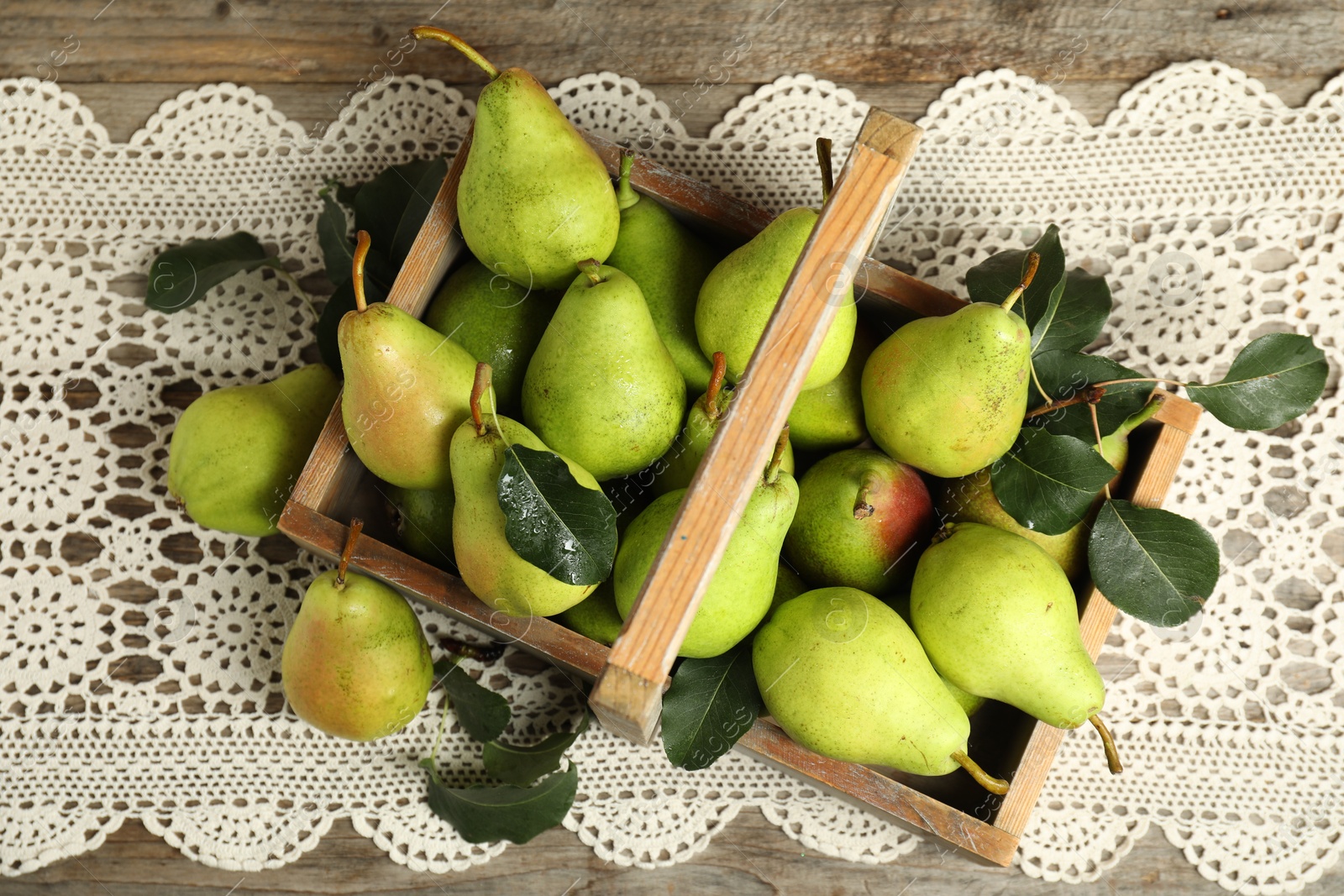 Photo of Crate with fresh green pears and leaves on wooden table, flat lay